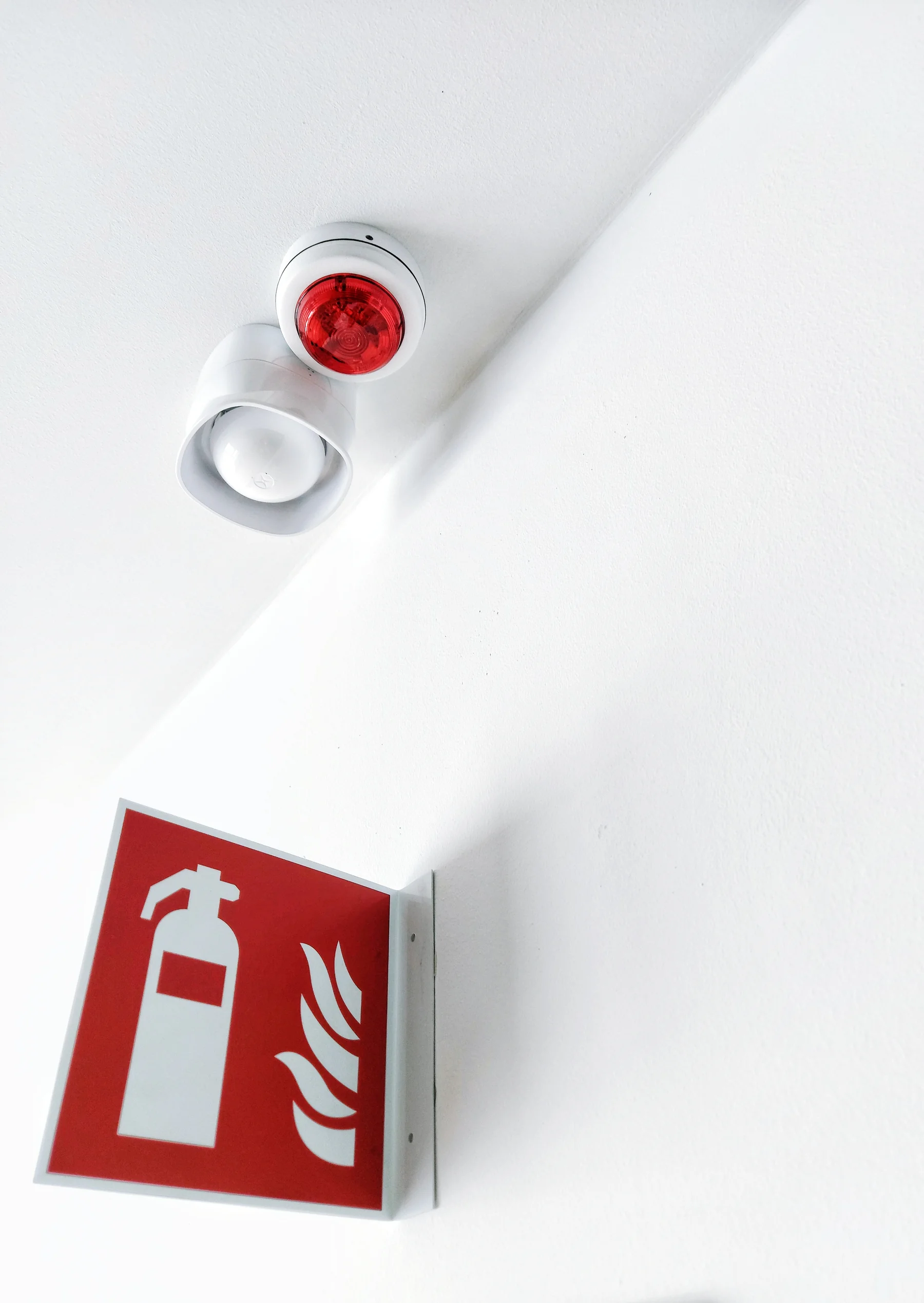 Sirène et flash d’alarme incendie au plafond, au-dessus d’un panneau de signalisation d’extincteur