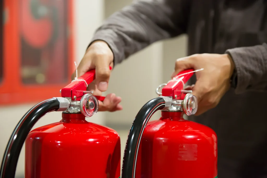Technicien vérifiant deux extincteurs rouges