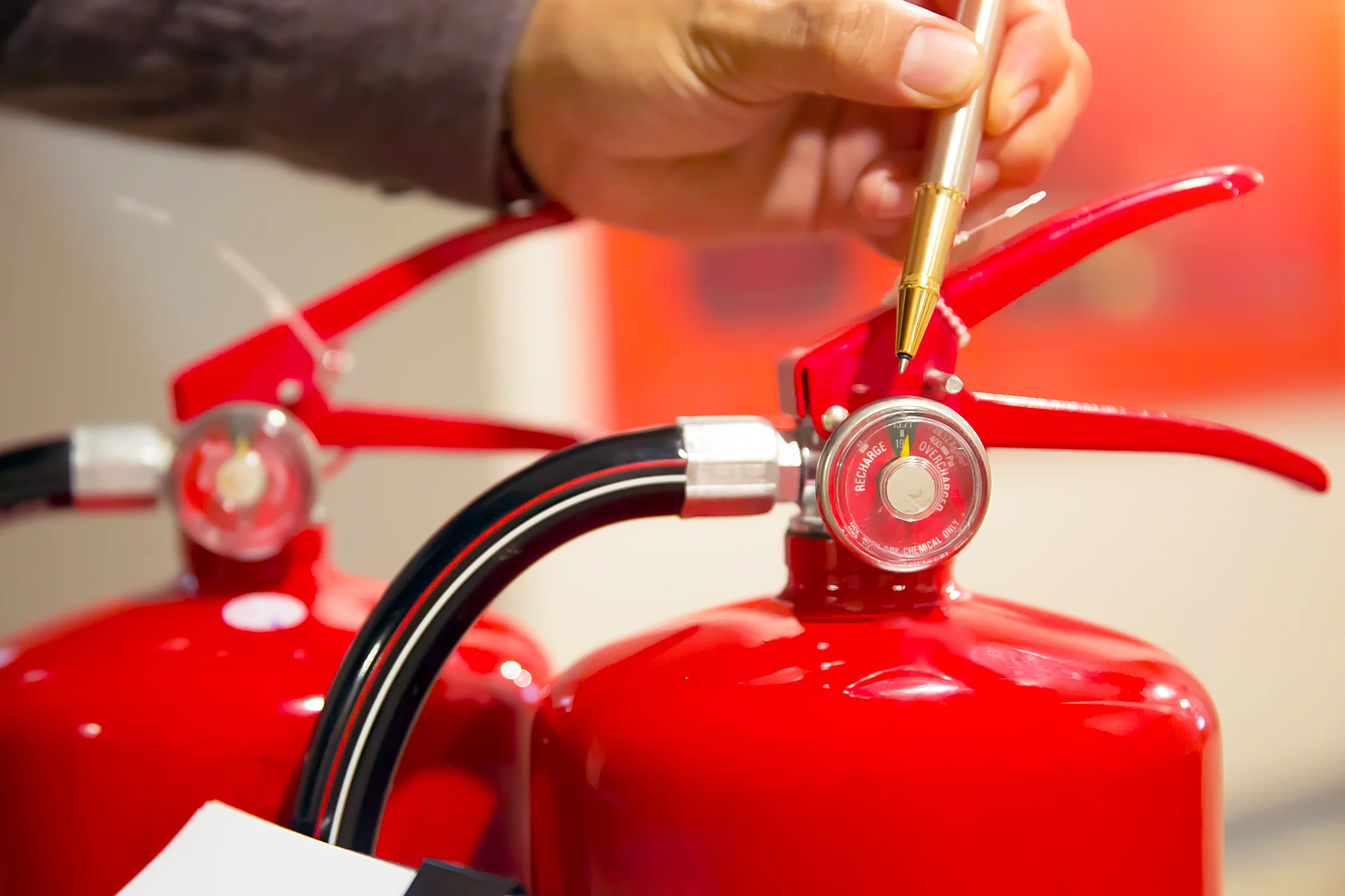 Technicien vérifiant au stylo le manomètre d’un extincteur rouge